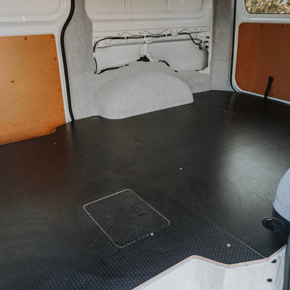 Interior of a van with black floor mat and white walls.