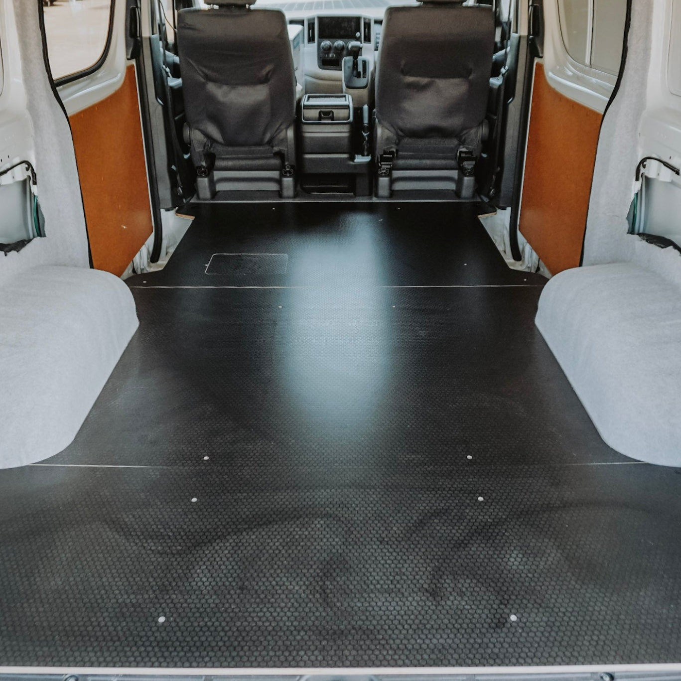 Van interior with a black floor mat and white walls.